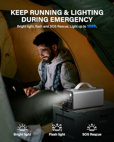 Man in tent using a laptop with an emergency light and power bank.