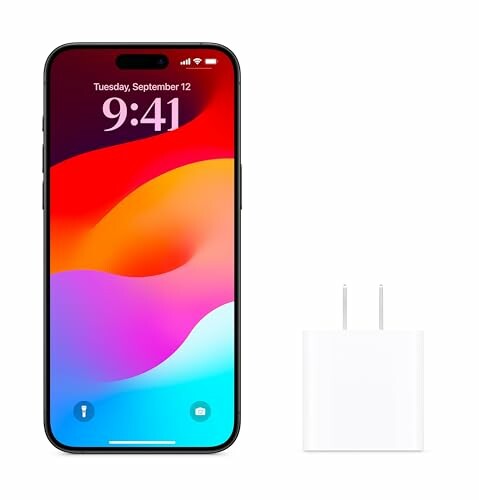 Smartphone with colorful display next to a charger