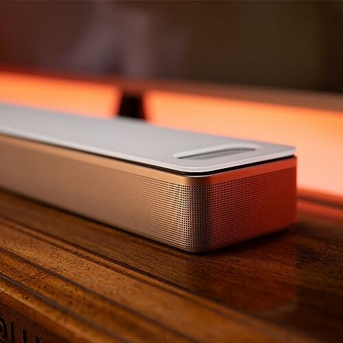 Modern soundbar on a wooden surface with warm lighting.