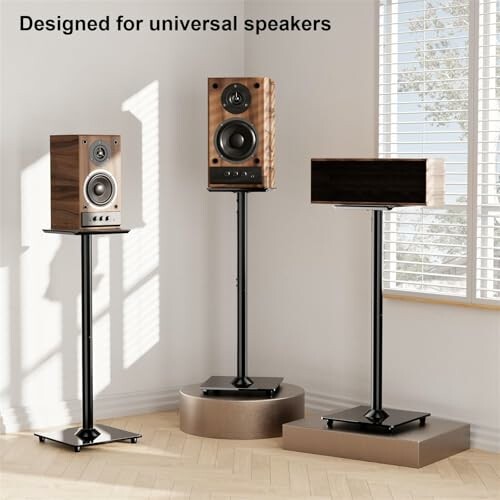 Three wooden speakers on stands in a sunlit room.