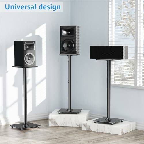 Three speaker stands with speakers in a well-lit room.