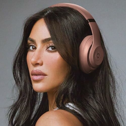 Woman with long dark hair wearing rose gold headphones.